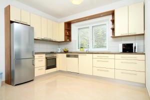 a kitchen with white cabinets and a stainless steel refrigerator at Apartments by the sea Lumbarda, Korcula - 9300 in Lumbarda