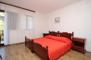 a bedroom with a red bed and a window at Apartments by the sea Prigradica, Korcula - 9288 in Blato
