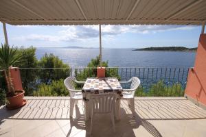 a table and chairs on a balcony with a view of the ocean at Seaside secluded apartments Grscica, Korcula - 9228 in Prizba