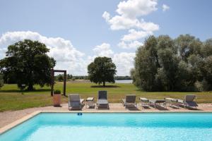 eine Gruppe von Stühlen und ein Pool mit Stühlen und Bäumen in der Unterkunft Le Noirlac in Saint-Amand-Montrond