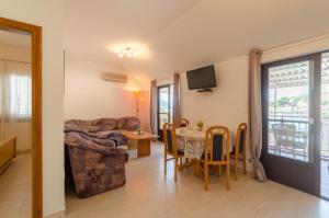 Apartments by the sea Brna, Korcula - 9162 في Smokvica: غرفة معيشة مع أريكة وطاولة مع كراسي