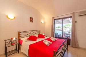 a bedroom with a bed with red pillows and a window at Apartments by the sea Brna, Korcula - 9162 in Smokvica
