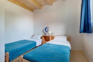 two beds in a small room with blue sheets at Apartment Nerezine 8049b in Nerezine