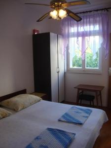 Schlafzimmer mit einem Bett, einem Deckenventilator und einem Fenster in der Unterkunft Apartments and rooms by the sea Sumartin, Brac - 2953 in Sumartin