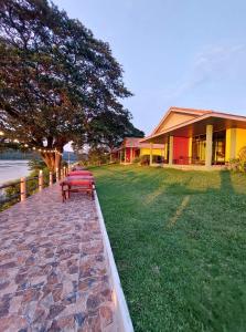 una casa con un banco en un campo de hierba en Khong Chiam Orchid Riverside Resort, en Khong Chiam