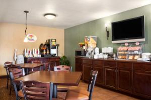 a restaurant with a table and a tv on a wall at Super 8 by Wyndham Fairview Heights-St. Louis in Fairview Heights