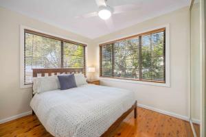 a bedroom with a bed and two large windows at Little Beach Bungalow - at Bartlett's in Bonny Hills