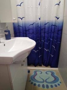 ein Badezimmer mit einem Waschbecken und einem Duschvorhang mit Vögeln in der Unterkunft Apartments by the sea Krapanj, Sibenik - 9258 in Brodarica