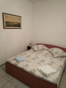 a bed in a bedroom with a picture on the wall at Apartments by the sea Krapanj, Sibenik - 9258 in Brodarica