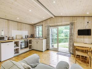eine Küche und ein Wohnzimmer mit einem Sofa und einem Tisch in der Unterkunft Lakeside Cabin in Dunkeswell