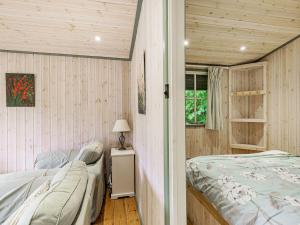two beds in a room with wooden walls at Lakeside Cabin in Dunkeswell