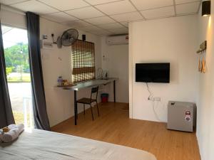 a room with a bed and a table and a desk at Raintown Cottage in Taiping
