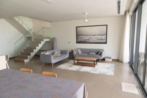 a living room with a couch and a staircase at Faru Beachfront Villa Sanctuary Ho Tram in Ho Tram