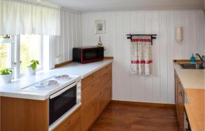 a kitchen with a stove and a microwave on a counter at Amazing Home In Hagalundmjölby in Mjölby