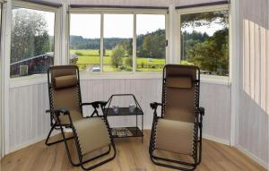 two chairs and a table in a room with windows at Amazing Home In Hagalundmjölby in Mjölby