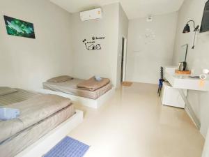 a white room with two beds and a sink at บ้านไม้หอมบูติค สวนผึ้ง in Ban Bo Wi