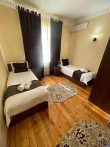 a bedroom with two beds and wooden floors at Zaringiz Boutique in Bukhara