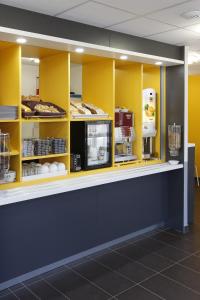 a counter with yellow shelves with food on it at B&B HOTEL Gap in Gap