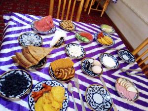 a table with plates of food on a purple and white table cloth at Fayz Guest House in Khiva