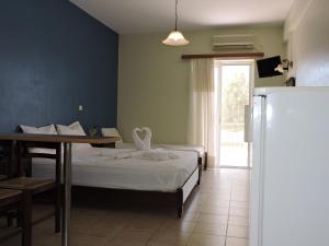 1 dormitorio con 1 cama, mesa y nevera en Sirios, en Finikounta