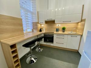 a kitchen with white cabinets and a black stool at Sasfeszek Apartman (Teljes lakás) in Szeged