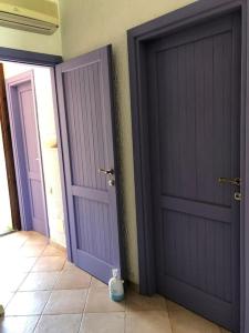 duas portas roxas num quarto com piso em azulejo em Villetta Reparata em Santa Teresa Gallura
