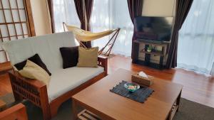 ein Wohnzimmer mit einem Sofa und einem Couchtisch in der Unterkunft Océanos - Sunset, BBQ, Beach & Kayak - オケアノス in Ishigaki-jima