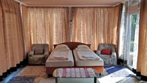 a bedroom with two beds and two chairs at Novákporta vendégház in Lakhegy