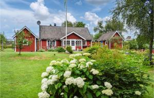 una casa roja con flores blancas delante en Bjrnhult,, en Tjörnarp
