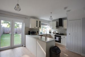 a kitchen with white cabinets and a counter top at SAXON ROAD - A 3 Bedroom House with Garden by Prestigious Stays - Includes Wifi, Netflix & Amazon Alexa in Sunbury Common