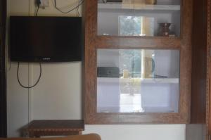 un salon avec une fenêtre et une télévision dans l'établissement Lakshmi Kutteer Homestay, à Nainital