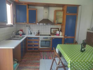 uma cozinha com armários azuis e uma mesa com uma toalha de mesa verde em Niforeika panorama em Kato Achaia