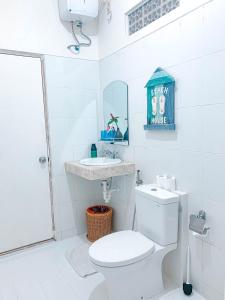 een witte badkamer met een toilet en een wastafel bij PIMA Homestay in Pesanggaran
