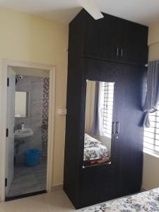 a bedroom with a black cabinet and a bathroom at Castle JP Deluxe in Bangalore