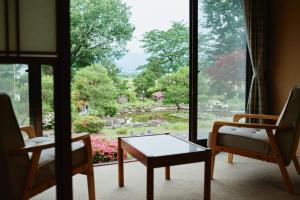 a room with two chairs and a table and a window at Takamiya Ryokan Sagiya Sansorai in Kaminoyama