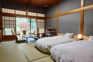 1 dormitorio con 2 camas y mesa en Takamiya Ryokan Sagiya Sansorai en Kaminoyama