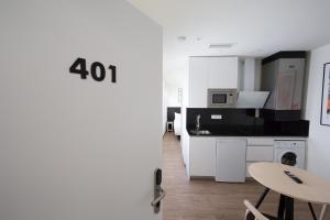 uma cozinha com armários brancos e uma mesa num quarto em Apartamentos Centro Jardines em Madrid