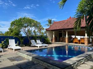 a swimming pool with two chairs and a house at Wonder Dive Bali Tulamben Villa's in Tulamben