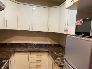 a kitchen with white cabinets and a black counter top at Al Rehab Apartments in Cairo
