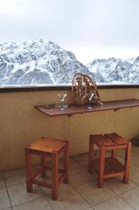 einen Tisch und zwei Hocker vor einem schneebedeckten Berg in der Unterkunft Granges 8 - BEL APPT 4P AU PIED DES PISTES DOMAINE ALPE D'HUEZ in Villard-Reculas