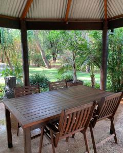 Mandurah Caravan and Tourist Park في ماندورا: طاولة خشبية مع كرسيين وجلسة تمثال فوق
