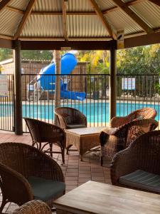 a patio with chairs and tables and a swimming pool at Mandurah Caravan and Tourist Park in Mandurah