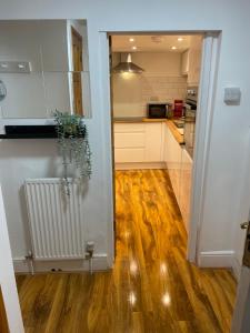 トーキーにあるGarden Flat Torquay Just 2 mins walk from the Harbourの白いキャビネットと木製の床を備えたキッチン +22枚の写真