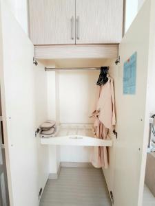 a small closet with white cabinets and pink clothes at Thipurai City Hotel in Hua Hin