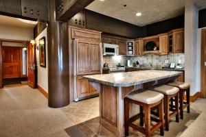 a kitchen with wooden cabinets and a large island with bar stools at Luxury Three Bedroom Suite with Mountain Views and Hot Tub apartment hotel in Park City