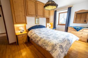 1 dormitorio con cama, suelo de madera y ventana en Casa Pergher, en Folgaria