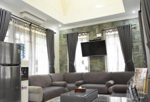 sala de estar con sofá y TV de pantalla plana en Diyar Villas Puncak M3/8, en Puncak