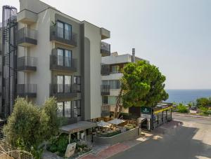 an apartment building with a tree next to a street at Sherwood Premio Hotel in Antalya