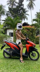 a man sitting on a motorcycle with a dog helmet on at Sean Sabai Home e Ristobar in Taling Ngam Beach