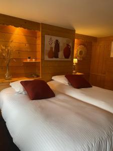 two beds in a bedroom with wooden walls at Hotel le P'tit Beaumont in Beaumont-en-Auge